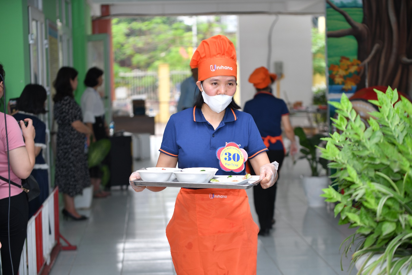 A person wearing a mask and holding a tray of food

Description automatically generated
